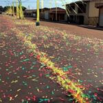 Rua em Ceilândia, Brasília, decorada para carnaval com confetes e bandeiras, representando exclusão de bloco.