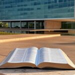 Fachada da Câmara Legislativa do DF em Brasília com Bíblia aberta, simbolizando patrimônio cultural e debate sobre laicidade.