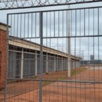 Imagem de presídio no Distrito Federal com portões fechados e cercas, representando calendário de saídas temporárias de presos.