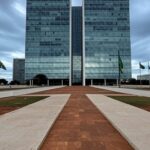 Prédio do Tribunal de Justiça em Brasília com bandeiras a meio mastro, representando luto por falecimento de desembargador.