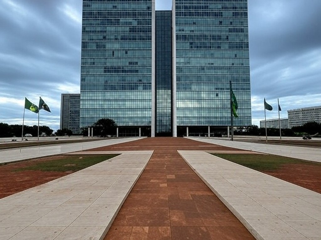 Prédio do Tribunal de Justiça em Brasília com bandeiras a meio mastro, representando luto por falecimento de desembargador.