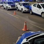 Viaturas do Detran-DF em blitz surpresa em Brasília, com uma colidida, cones de sinalização e avenida noturna.