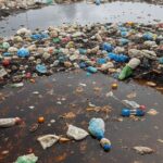 Cratera em rua de Ceilândia com lixo acumulado causando alagamentos, em Brasília.