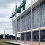Fachada da CLDF em Brasília com ruas vazias simbolizando crises econômicas e anúncio de concurso fotográfico.