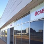 Fachada de posto de atendimento da Caesb em Brasília com relógios indicando horários ampliados de atendimento presencial no DF.
