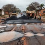 Rua em Ceilândia com operação tapa-buraco aplicando asfalto para reparar danos causados pelas chuvas.