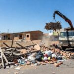 Rua em Ceilândia com pilhas de entulho sendo recolhidas por caminhão, totalizando 147 toneladas em manutenção urbana.