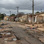 Rua deteriorada em Riacho Fundo I, Brasília, expondo demandas não atendidas no aniversário de 36 anos.