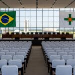 Auditório em Brasília preparado para cerimônia de formatura do Programa Qualifica DF, com bandeiras e decoração.