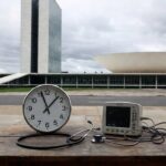 Edifício governamental em Brasília com relógio parado e equipamentos médicos, simbolizando falhas em diagnósticos de cardiopatias para bebês com Down.