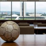 Bola de futsal desgastada em sala da Câmara Legislativa do DF, representando crise de investimentos no esporte.